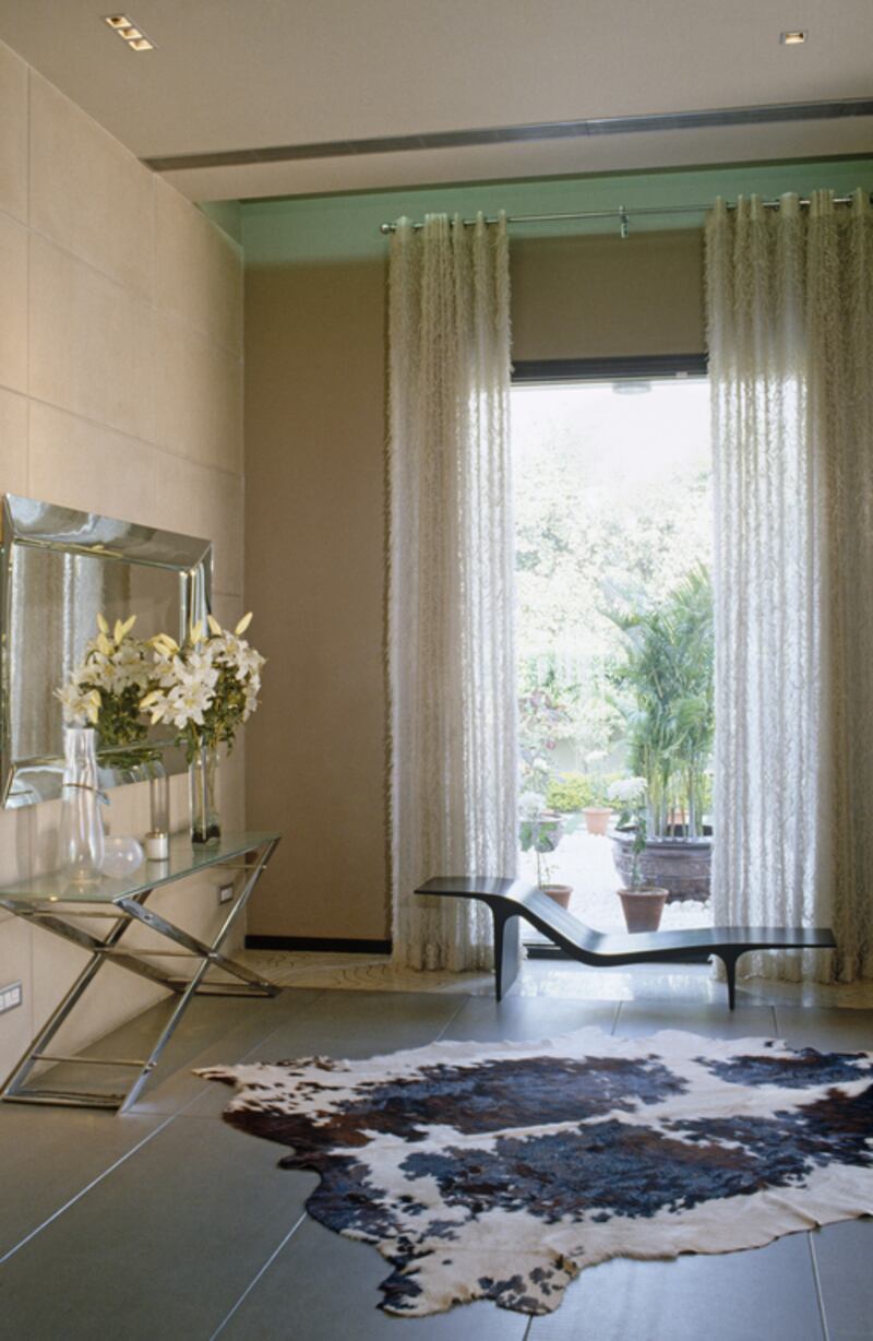 Stylish seating in front of window with full length curtains in modern sitting room.