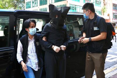 Hong Kong police officers accompany a hooded suspect during a search for evidence over the publication of children’s books deemed to be seditious. AP Photo
