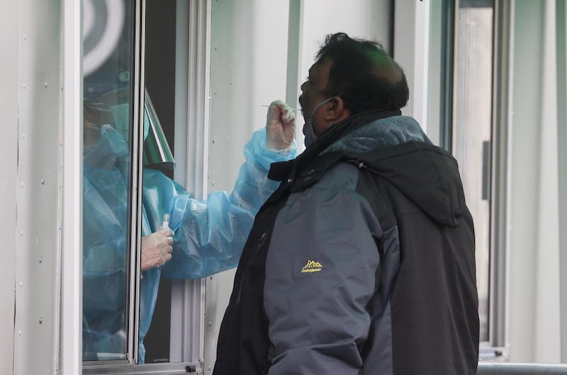 A health care worker takes a swab sample from a man to test for coronavirus at a mobile testing site at Heathrow Airport. Reuters