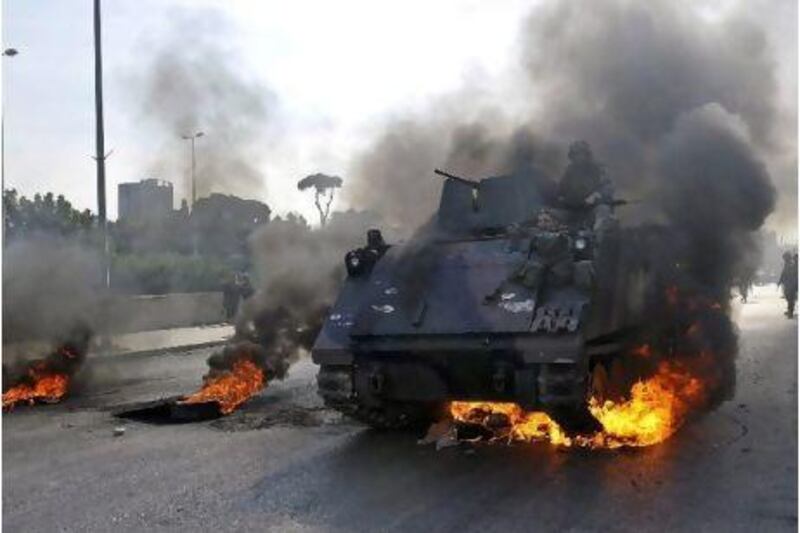 A tank passes burning tyres in Beirut. Tanks are stationed in politically sensitive areas in the Lebanese capital.