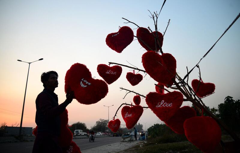 An Indian vendor adjusts heart-shaped pillows hanging from a tree at a roadside stall ahead of Valentine's Day in Jalandhar on February 9, 2018. / AFP PHOTO / Shammi MEHRA