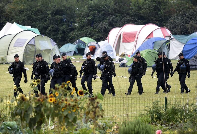 French gendarmes walk by tents during the evacuation of the Grande Synthe migrant camp, northern France, on September 17, 2019. / AFP / FRANCOIS LO PRESTI
