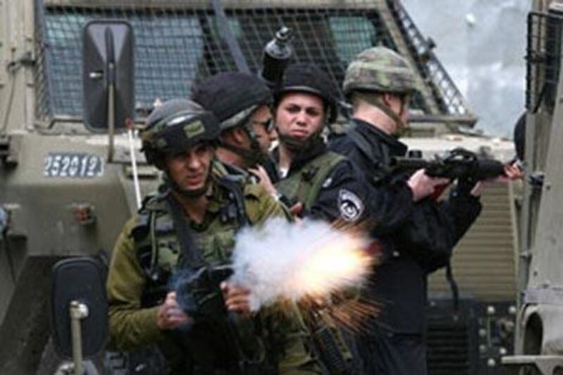 An Israeli soldier fires tear gas at Palestinian stone-throwers during  clashes over the last two days in Hebron, West Bank.