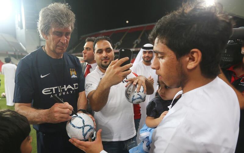 Manchester City manager Manuel Pellegrini autographs a ball for a fan. Marwan Naamani / AFP