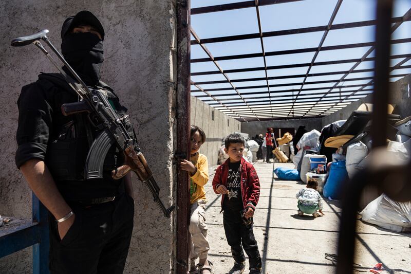 A Syrian Democratic Forces member stands guard over family members of suspected ISIS fighters before they are transferred from Al Hol camp. AP