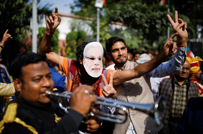A supporter of India's ruling party Bharatiya Janata Party, behind a mask of Prime Minister Narendra Modi, celebrates after hearing the initial poll results at the party headquarters in New Delhi on March 10. Reuters