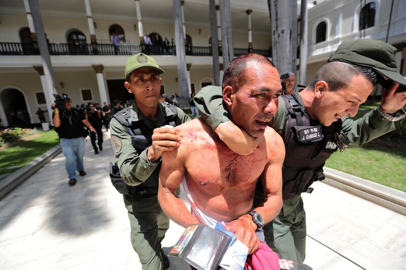 A supposed government supporter who was part of a group that tried to force its way into the National Assembly, is temporarily detained by national guardsmen, but let go soon after, in Caracas, Venezuela, Wednesday, July 5, 2017. Pro-government militias wielding wooden sticks and metal bars violently stormed congress and began attacking opposition lawmakers at the end of a special session coinciding with Venezuela’s independence day. (AP Photos/Fernando Llano)