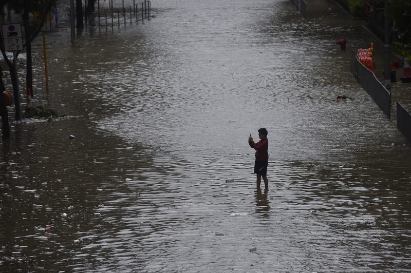 A man takes a photo while standing in a flooded street in the Heng Fa Chuen area as Typhoon Hato hits Hong Kong. Anthony Wallace / AFP.