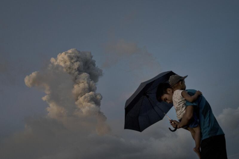 Boys take cover with an umbrella as the Mayon volcano spews ash and lava. Jes Aznar / Getty Images