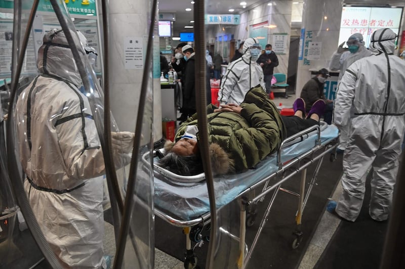 Medical staff members wearing protective clothing to help stop the spread of a deadly virus which began in the city, arrive with a patient at the Wuhan Red Cross Hospital in Wuhan.  AFP
