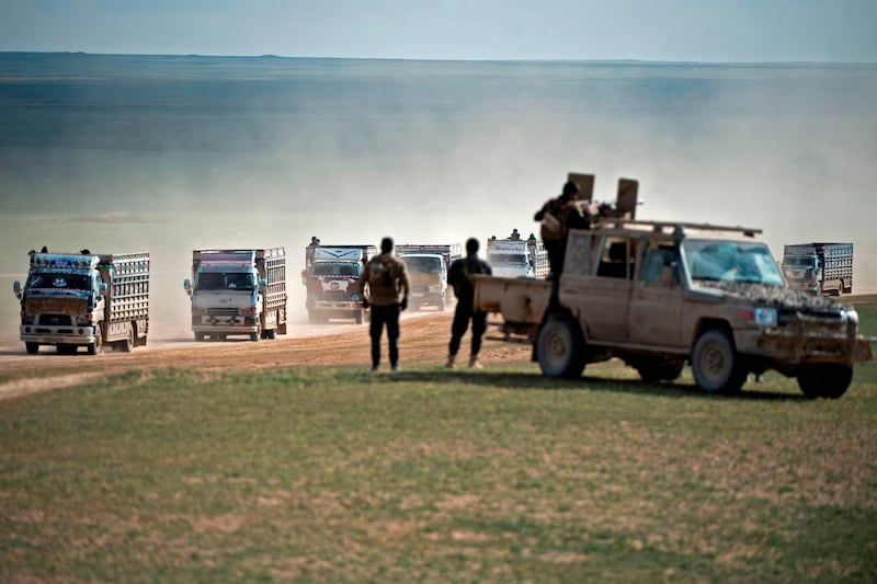 SDF fighters stand guard as a convoy of trucks transports civilians fleeing the battered ISIS held holdout of Baghouz in the eastern Syrian province of Deir Ezzor. APF