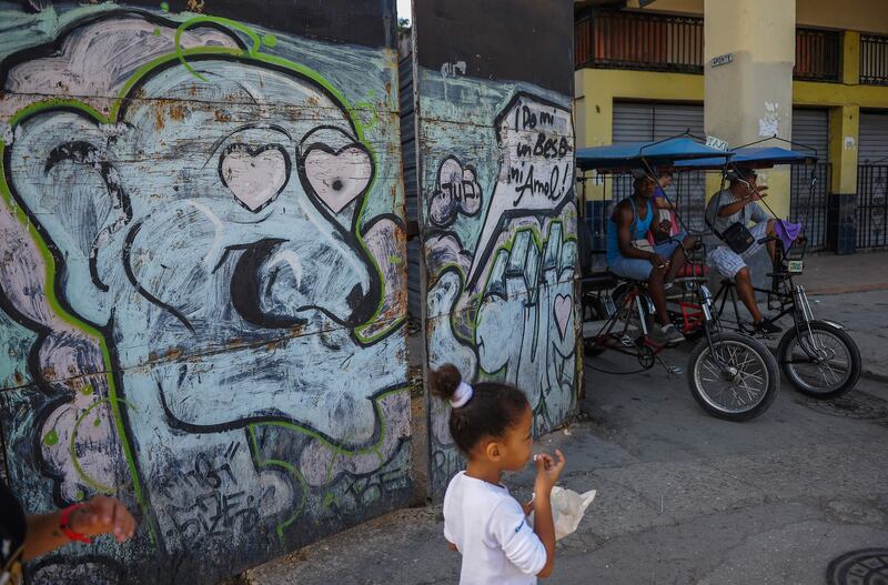 Rickshaws are parked near a graffiti of street art in Havana, on July 12, 2017. / AFP PHOTO / YAMIL LAGE