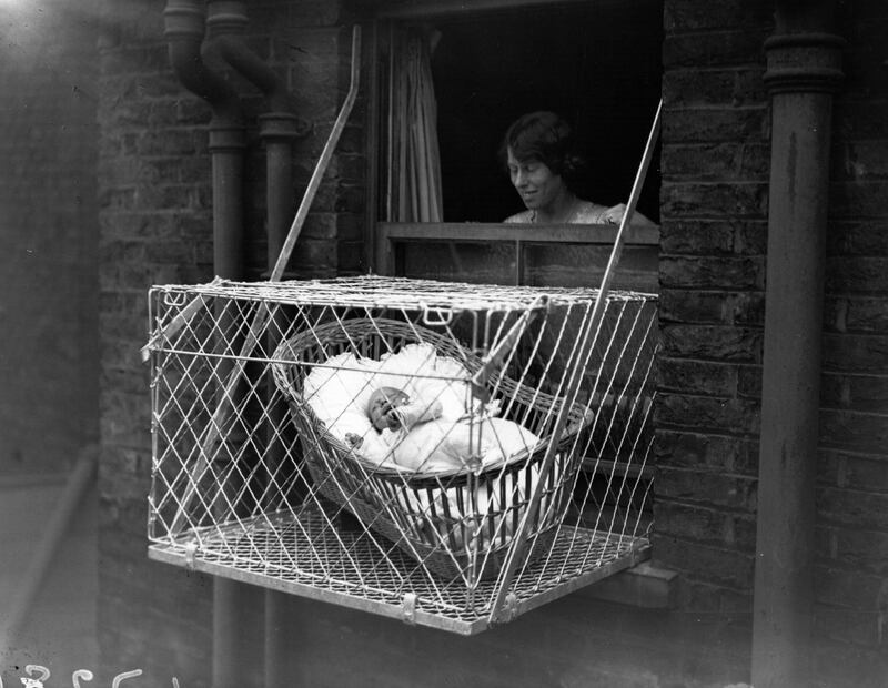 June 1923:  A baby in its cot on a ledge outside a window in Bloomsbury, London.  (Photo by Topical Press Agency/Hulton Archive/Getty Images)
