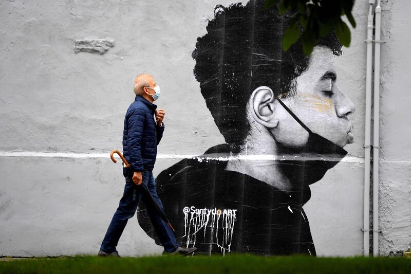 A man with a face mask walks past a mural by @SentydoART depicting a boy with his face mask downward, in Oviedo, Spain. Spanish Government passed a new law that allows people to go without facial masks outdoors as long as social distancing is possible.  EPA