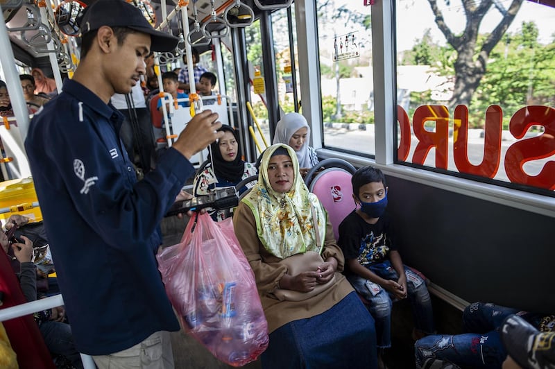 A bus conductor collects used plastic bottles as fare payment on board a Suroboyo bus in the Indonesian city of Surabaya. All photos by AFP