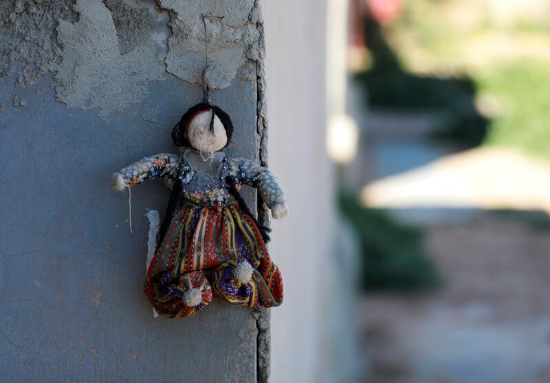 A doll hangs from a wall of a house in Jinwar village
