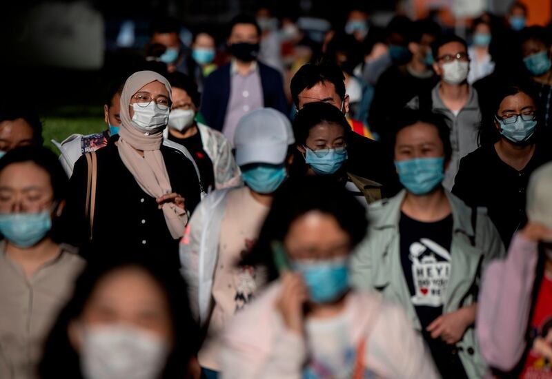 People wearing facemasks walk to the subway during a rush hour in Beijing.   AFP