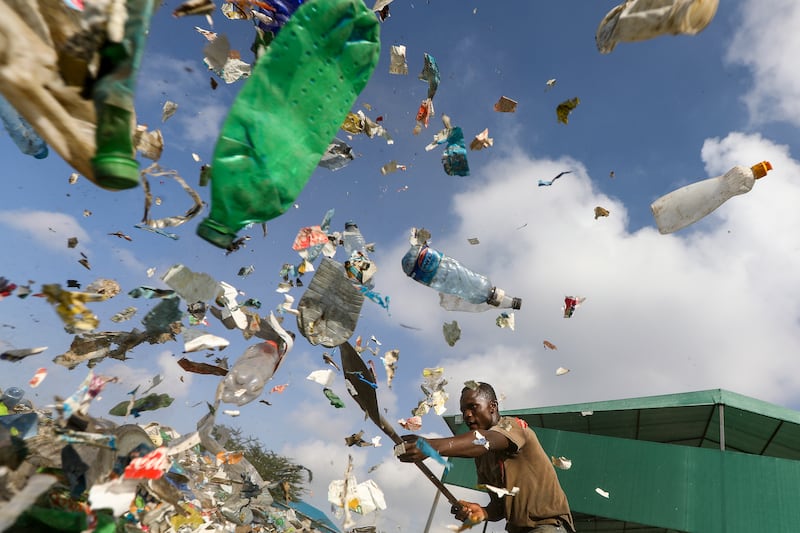 A worker shovels plastic bottles at a company that recycles them in Machakos, Kenya. EPA