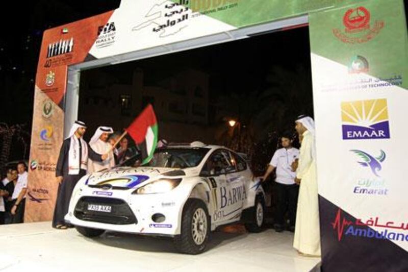 Sheikh Mansour bin Mohammed, left, and Mohammed ben Sulayem, the former UAE rally driver, second left,drop the flag for Nasser Al Attiyah at the ceremonial start of the Dubai International Rally Thursday night.