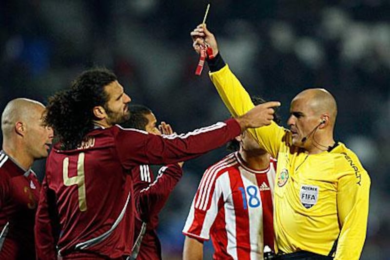 Referee Francisco Chacon, of Mexico, right, issues a yellow card to Venezuela's Roberto Rosales, left, partially obscured by teammate Oswaldo Vizcarrondo. Fernando Llano / AP Photo