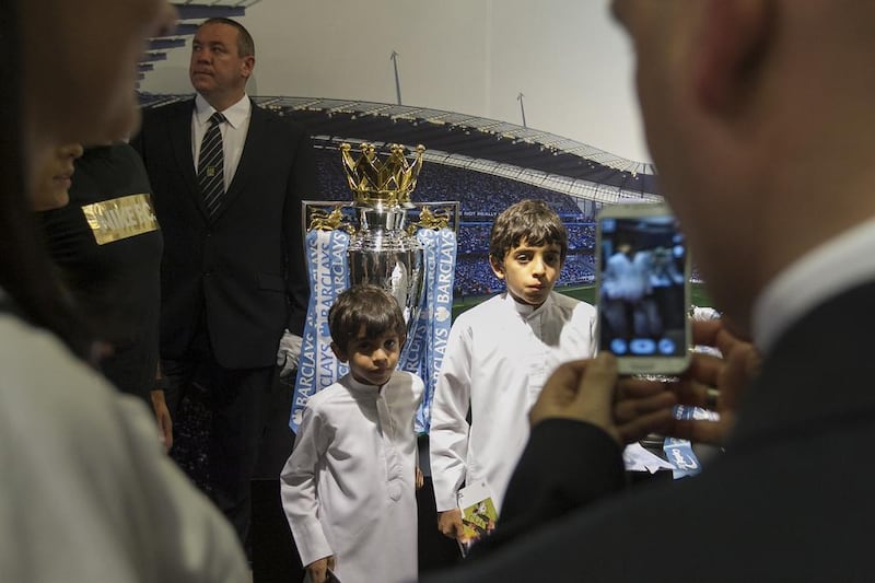 Two young Emirati Manchester City fans get their picture taken with the Premier League trophy, which was on hand for a player appearance at Marina Mall in Abu Dhabi on Tuesday. Mona Al-Marzooqi / The National / May 13, 2014

