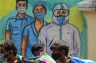 Pedestrians walk past a wall mural depicting medical staff as frontline Covid-19 coronavirus warriors, in Mumbai on March 21, 2021.  / AFP / Indranil MUKHERJEE
