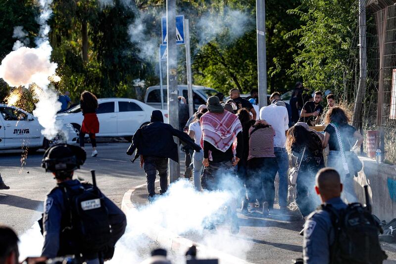 Israeli security forces fire tear gas as Palestinian protesters and activists flee, near an Israeli Police checkpoint at the entrance of the Sheikh Jarrah neighbourhood in east Jerusalem, during a rally demanding the reopening of the roadblock, on May 29, 2021. Tensions between Israel and Palestinians that lead to 11 days of military violence initially flared in the Sheikh Jarrah neighbourhood of occupied east Jerusalem, where Israeli police cracked down on people protesting the planned expulsion of Palestinian families from their homes so Jewish settlers could move in. / AFP / Ahmad GHARABLI
