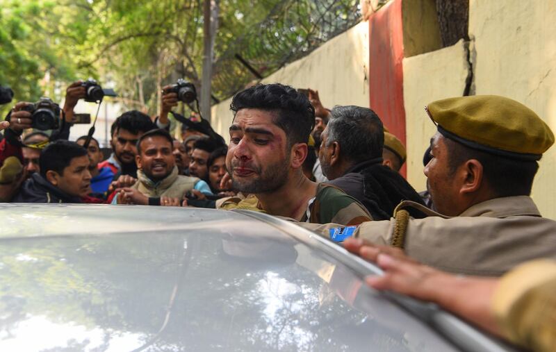 An injured man (C) that an angry mob had attacked, believing him to be a Kashmiri who had shouted pro-Pakistan slogans, is shielded by Indian policemen in New Delhi on February 17, 2019. Protesters in the Indian capital on February 17 beat up a man they accused of being a Kashmiri and shouting pro-Pakistan slogans, amidst a demonstration in reaction to the February 14 suicide bombing attack on paramilitary troops in Kashmir that left 41 soldiers dead. / AFP / Sajjad HUSSAIN
