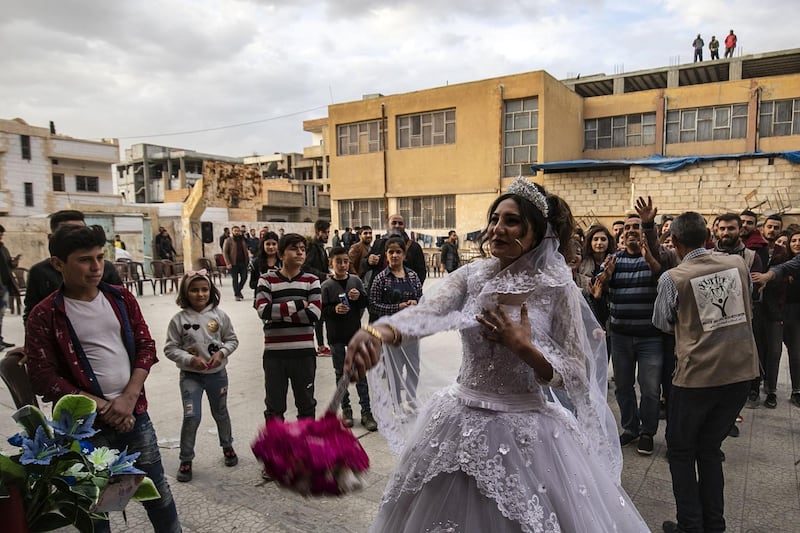 The newly wedded Hanan tosses her bouquet of flowers in front of a school buidling,  transformed into a makeshift shelter for displaced people, on their wedding day in the northern Syrian city of Hasakeh.  AFP