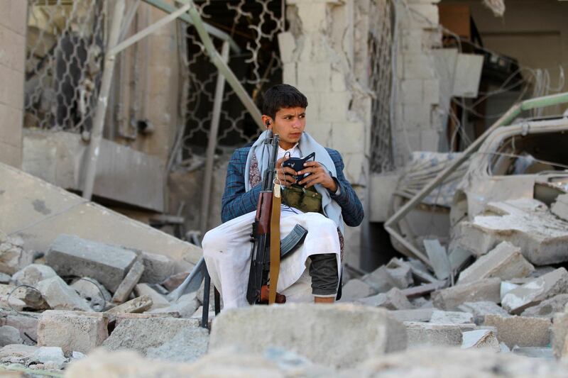 An armed Yemeni youth, loyal to the Shiite Muslim Huthi movement that controls Sanaa, sits amid the rubble on December 5, 2014, guarding the damaged house of the Iranian ambassador in the Yemeni capital which was targeted by a car bomb earlier this week. Al-Qaeda's local branch said on December 3  it was behind a car bombing that killed one person and wounded 17 outside the residence of Iran's ambassador the Yemeni capital, where Tehran is accused of backing Shiite militia.  AFP PHOTO / MOHAMMED HUWAIS (Photo by MOHAMMED HUWAIS / AFP)