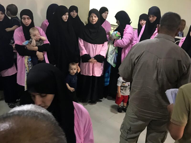A picture taken on April 29, 2018 in the Iraqi capital Baghdad's Central Criminal Court shows Russian women who have been sentenced to life in prison on grounds of joining the Islamic State (IS) group standing with children in a hallway.
Iraq sentenced 19 Russian women to life in prison for joining IS group on April 29, according to an AFP journalist and a judicial source. 
The president of Baghdad's Central Criminal Court, which deals with terrorism cases, said the women were found guilty of "joining and supporting IS". / AFP PHOTO / Ammar Karim