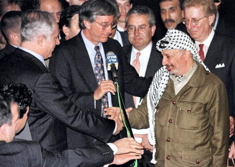 Palestinian President Yasser Arafat (R) shakes hands with Israeli Prime Minister Benjamin Netanyahu after United States' special envoy Dennis Ross (C) spoke, early January 15 after the two leaders met and agreed on the term for the long overdue Israeli troop redeployment in Hebron. The talks lasted less than two hours and concluded months of negotiations which will lead to the end of the Israeli military occupation in about 80 percent of Hebron.

MIDEAST