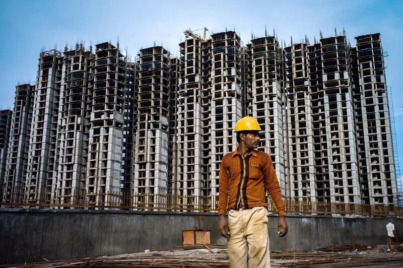 A construction worker stands on the construction site of a housing block in Sector 105 of Noida, in Uttar Pradesh, India. Sanjit Das / Bloomberg