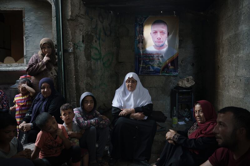 Members of the Nassir family sit under a poster of Mohamed Nassir, who died in the 11-day war. AP