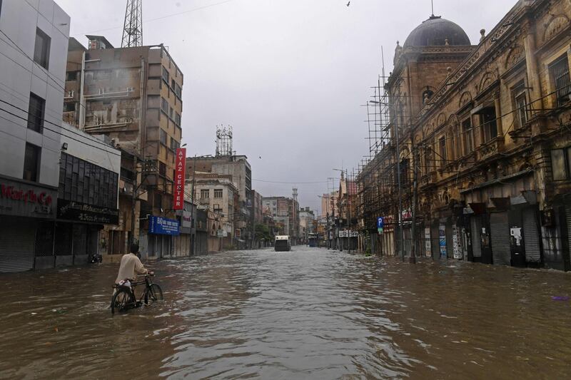 A commuter makes his way through a flooded street after heavy rain in Karachi, Pakistan, where the death toll from rain-related incidents has risen to at least 150 over the past month. AFP