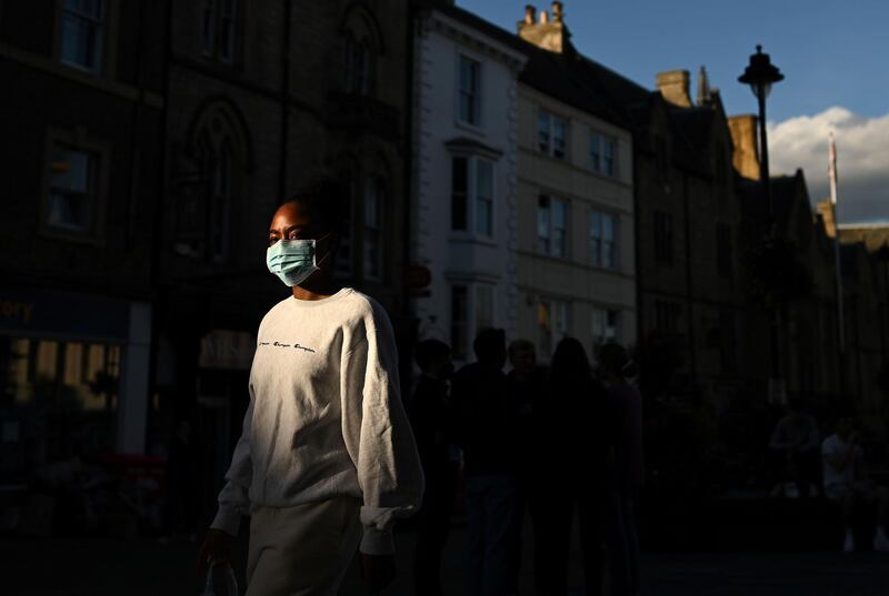 A woman wearing a face mask walks in the evening sunshine in Durham. AFP