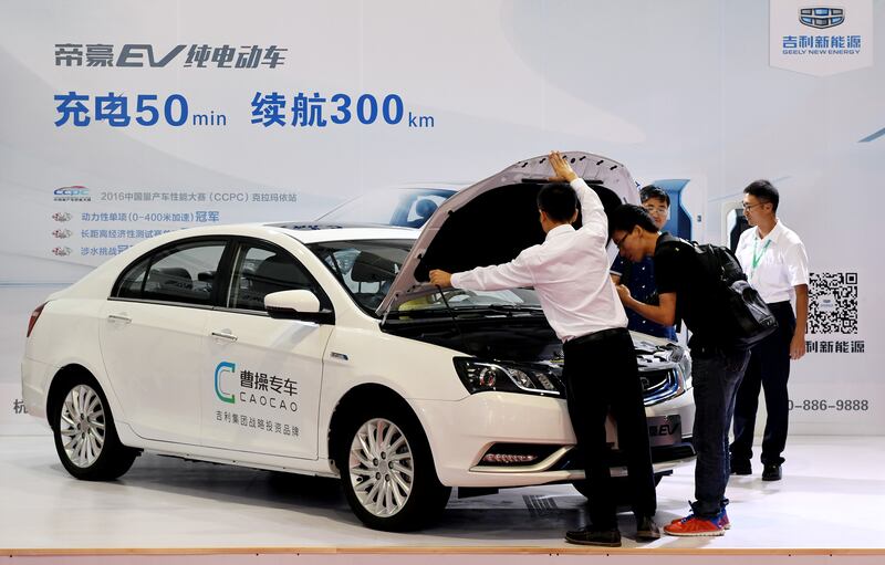 Men look at an electric vehicle of Caocao Zhuanche, a chauffeur ride-hailing platform backed by Zhejiang Geely Holding Group, at a new energy vehicle (NEV) trade fair in Zhengzhou, Henan province, China September 23, 2016. Picture taken September 23, 2016. REUTERS/Stringer  ATTENTION EDITORS - THIS IMAGE WAS PROVIDED BY A THIRD PARTY. CHINA OUT.