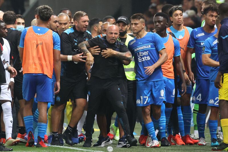 Marseille's French midfielder Dimitri Payet (2nd R) and Turkish forward Cengiz Under (17) stand by coach Jorge Sampaoli (C) as he is led by a colleague. AFP