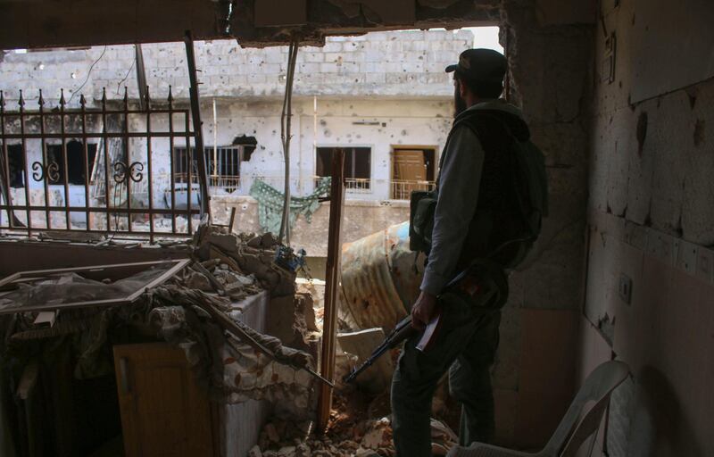 An opposition fighter looks out from a destroyed building in a rebel-held area in the southern Syrian city of Daraa on April 22, 2018. 
After the capture of Eastern Ghouta the Syrian president now has forces ready to redeploy elsewhere in the war-ravaged country. The Islamists and jihadists that hold the northwest province of Idlib remain a threat, but analysts say the Syrian president's priority will likely be the southern province of Daraa, where protests against his rule first broke out in 2011. / AFP PHOTO / Mohamad ABAZEED