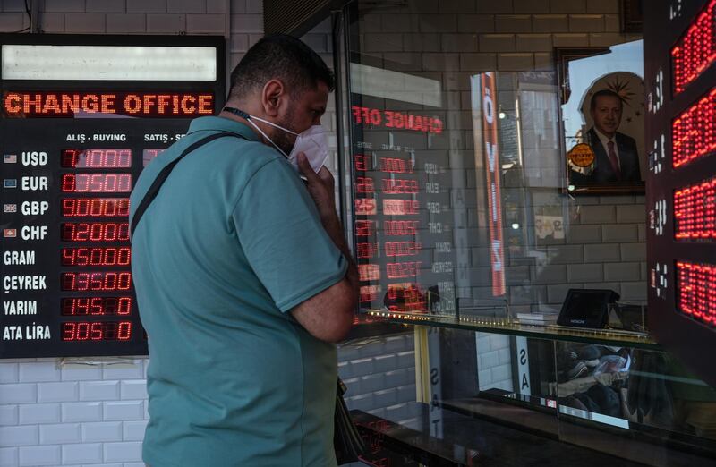 A man wearing face mask exchange his money, a picture of Turkish President Recep Tayyip Erdogan is seen in the background, at an exchange office in Istanbul.  EPA