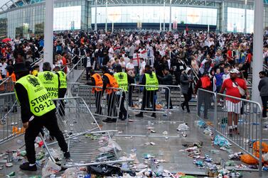 FILE - In this Sunday, July 11, 2021 file photo, stewards replace barricades after they were knocked over by supporters outside Wembley Stadium in London, during the Euro 2020 soccer championship final match between England and Italy.  UEFA has ordered England to play one men’s national team game in an empty stadium.  It's punishment for chaotic disorder around Wembley Stadium at the European Championship final in July.  The stadium closure will apply for a Nations League fixture in June.  A second empty-stadium game was deferred for a two-year probationary period.  Thousands of English fans tried to break through barriers to get into Wembley which was hosting the Euro 2020 final against Italy at about two-thirds capacity.  (AP Photo / David Cliff, File)