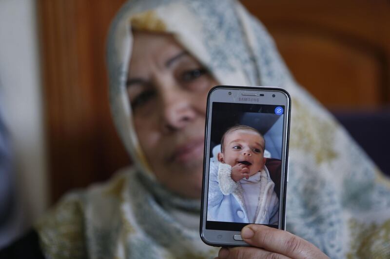 The grandmother of nine months old Palestinian baby Omar Yagi displays a picture of him in Gaza City on June 22, 2020. Baby Omar Yaghi was eight months old when he died, unable to travel from Gaza to Israel for life-saving heart surgery after Palestinian officials cut coordination. Yaghi was born with complex heart problems and he started treatment at Israel's Sheba Medical Center when he was just one month old. Having been unable to return for the surgery, Yaghi suffered heart failure on June 17 and was resuscitated at a Gaza hospital. / AFP / MOHAMMED ABED
