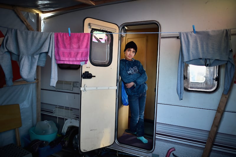 A boy looks out from a camper van as migrants contend with cold weather in December 2015