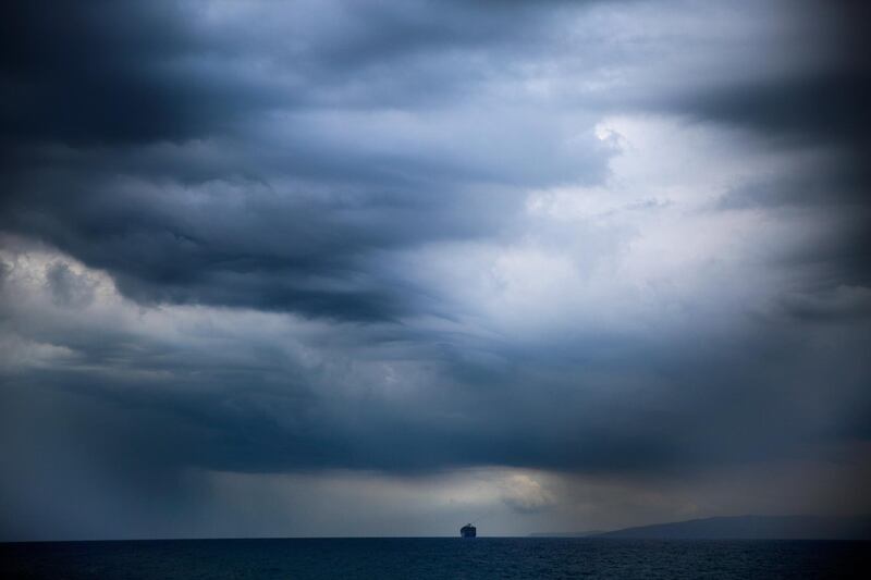 Dark clouds hover over a cargo ship as it navigates the Mediterranean Sea along the Beirut coastline, Lebanon, Thursday, Oct. 25, 2018. (AP Photo/Hassan Ammar)