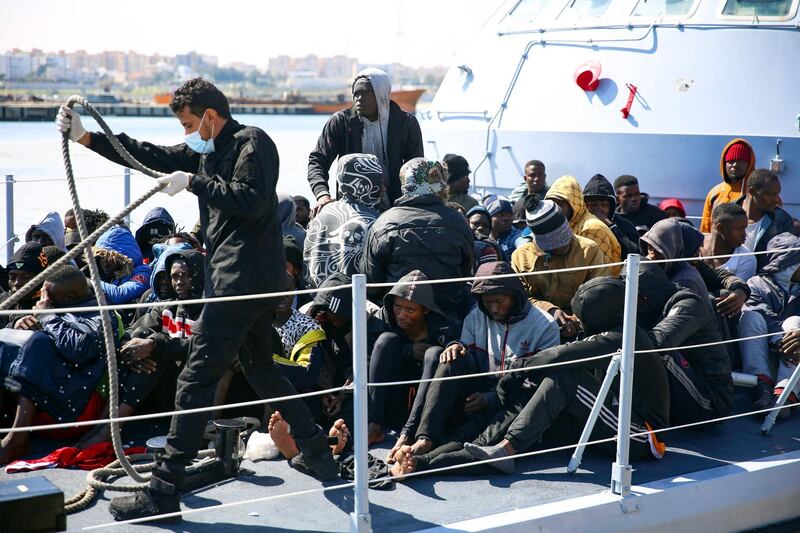 Rescued migrants sit aboard a Libyan coastguard vessel upon its arrival at the capital Tripoli's naval base on February 28, 2021.  / AFP / Mahmud TURKIA
