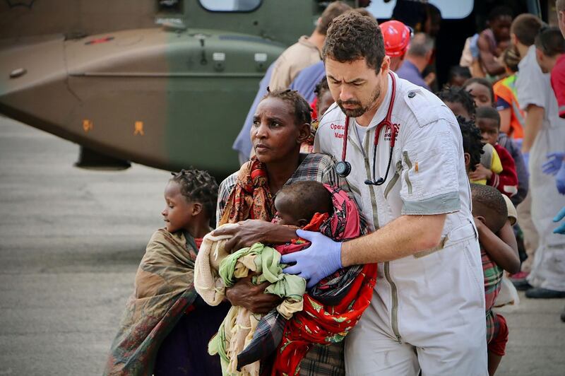 People are escorted to safety by aid workers at the airport of the coastal city of Beira in central Mozambique. AFP
