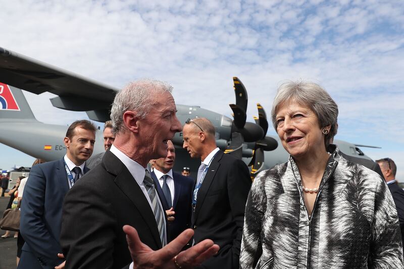 British prime minister Theresa May talks with guests as she opens the 2018 Farnborough Airshow. An Airbus A-400 Atlas looms in the background.