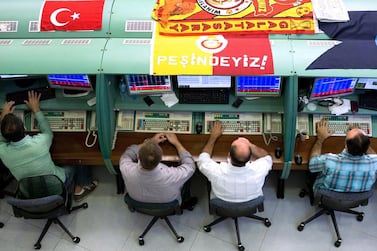 Flags decorate the working areas of traders as they monitor financial information on the floor of the Borsa Istanbul, the stock exchange in Istanbul. A bank on shorting seven domestic banks last month initially pushed up their shares, helped by a broader market gain, but volumes slumped before later recovering. Bloomberg