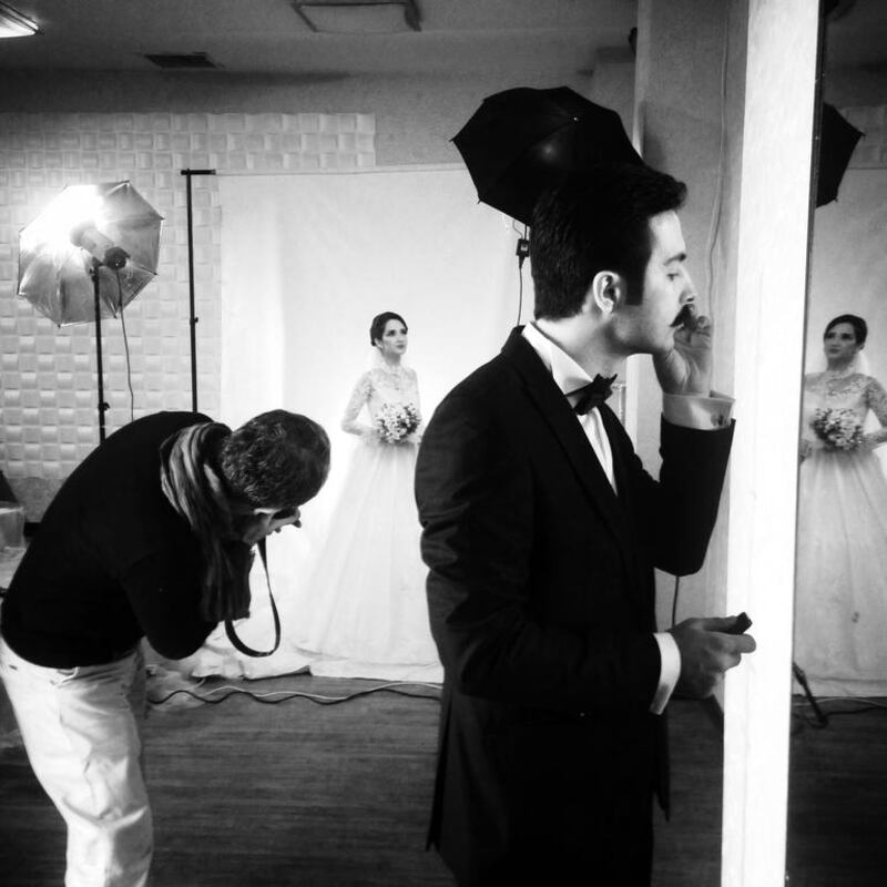 An Iranian groom, Mohammad, 26, looks at himself in a mirror while a bride Mona, 25, poses for a photographer during a wedding photo shoot in Tehran, Iran. Photo by Hanif Shoaei, (@HanifShoaei), March 2014.