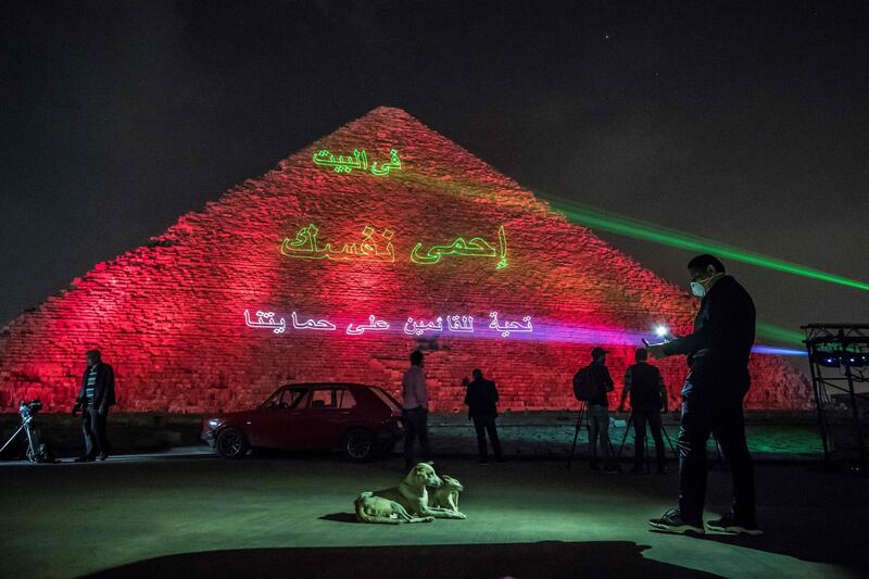 A man takes pictures of dogs in front of the Great pyramid of Kheops. AFP